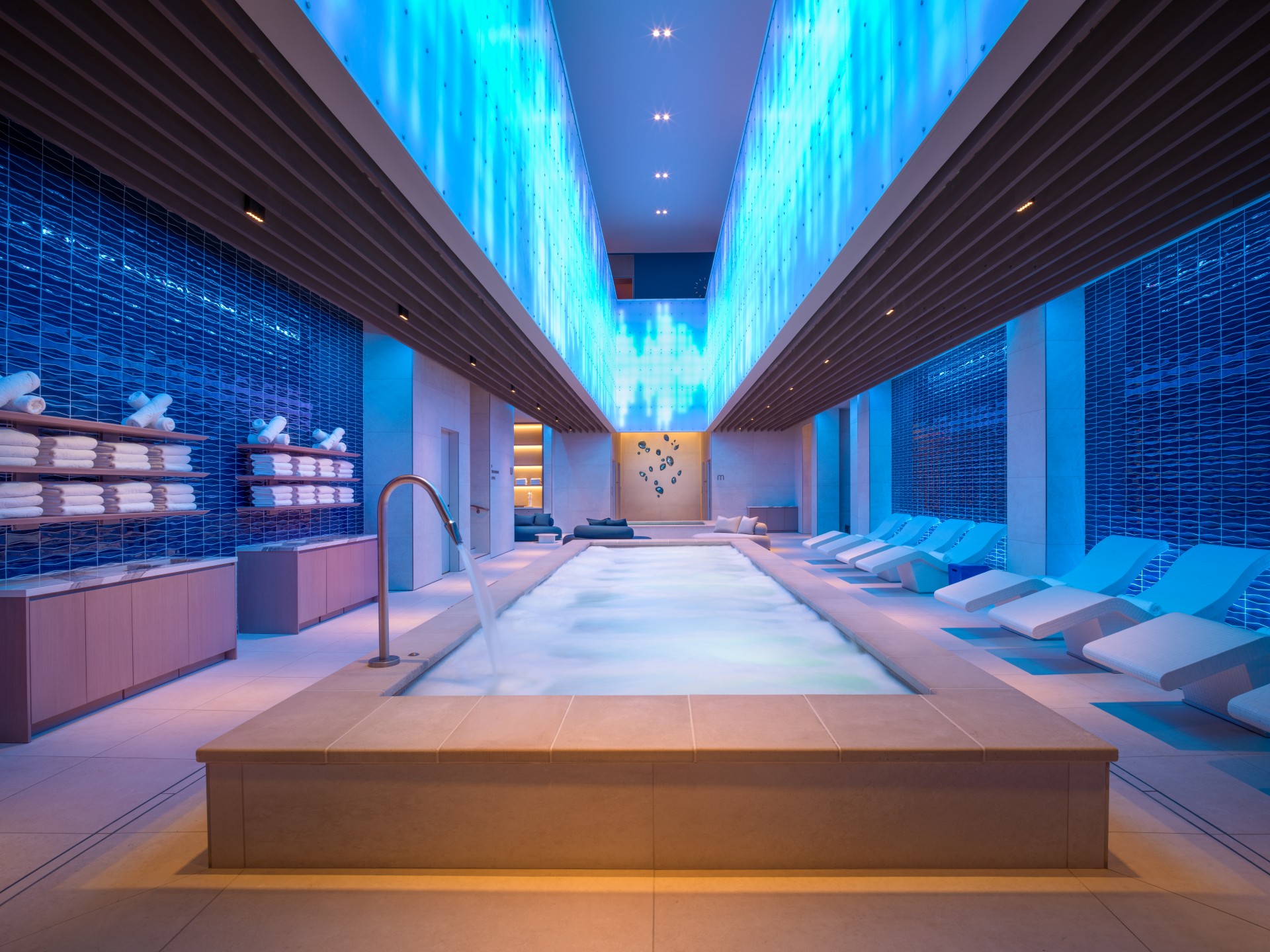 a pool with a large tub and chairs in a room