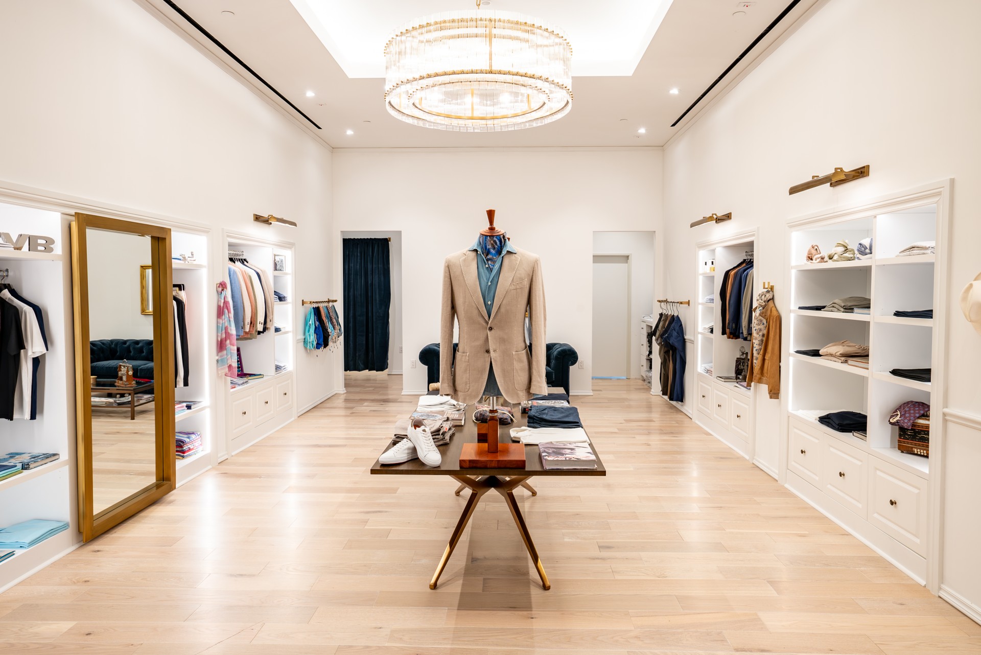 a room with a mannequin in a suit and a table with clothing