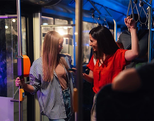 a woman standing next to another woman on a bus