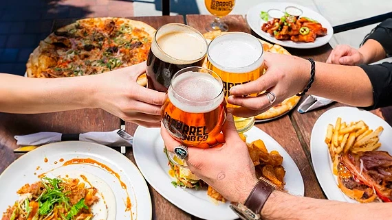a group of people holding glasses of beer and food