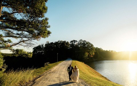 a bride and groom walking down a dirt road