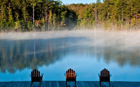 a group of chairs on a dock overlooking a lake