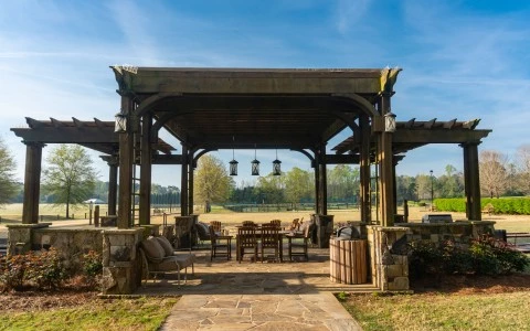 a wooden gazebo with a table and chairs under a stone patio