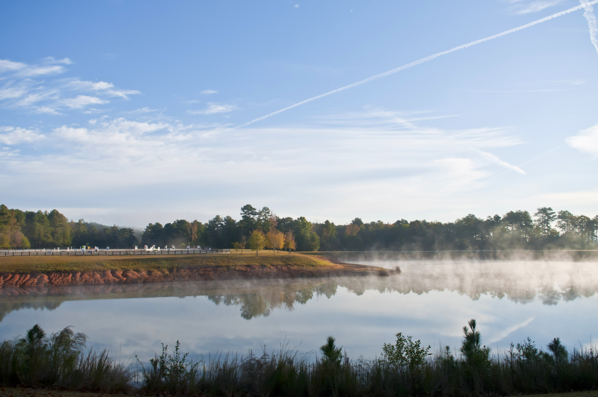 a body of water with fog and trees in the background