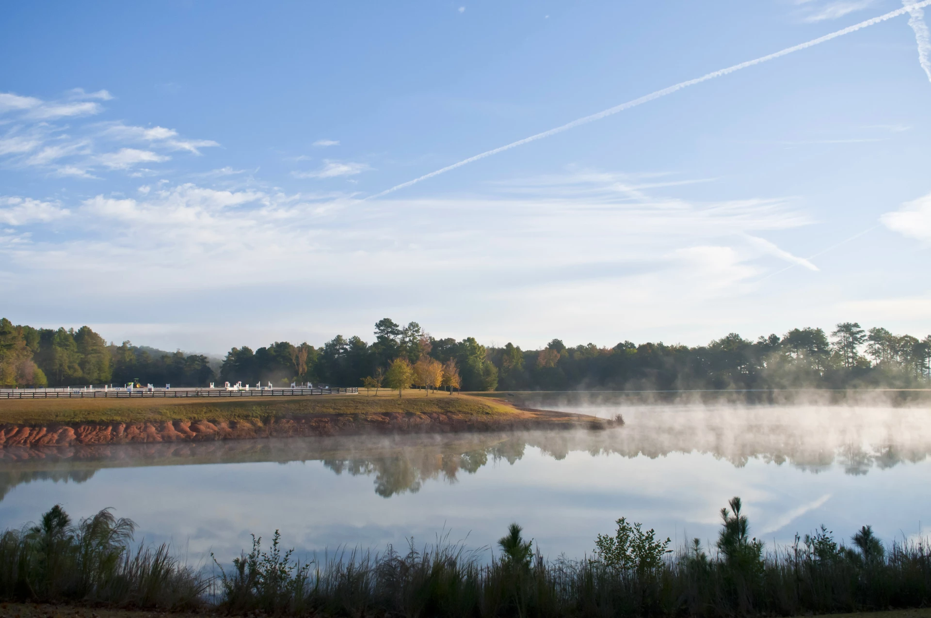 a body of water with fog and trees in the background