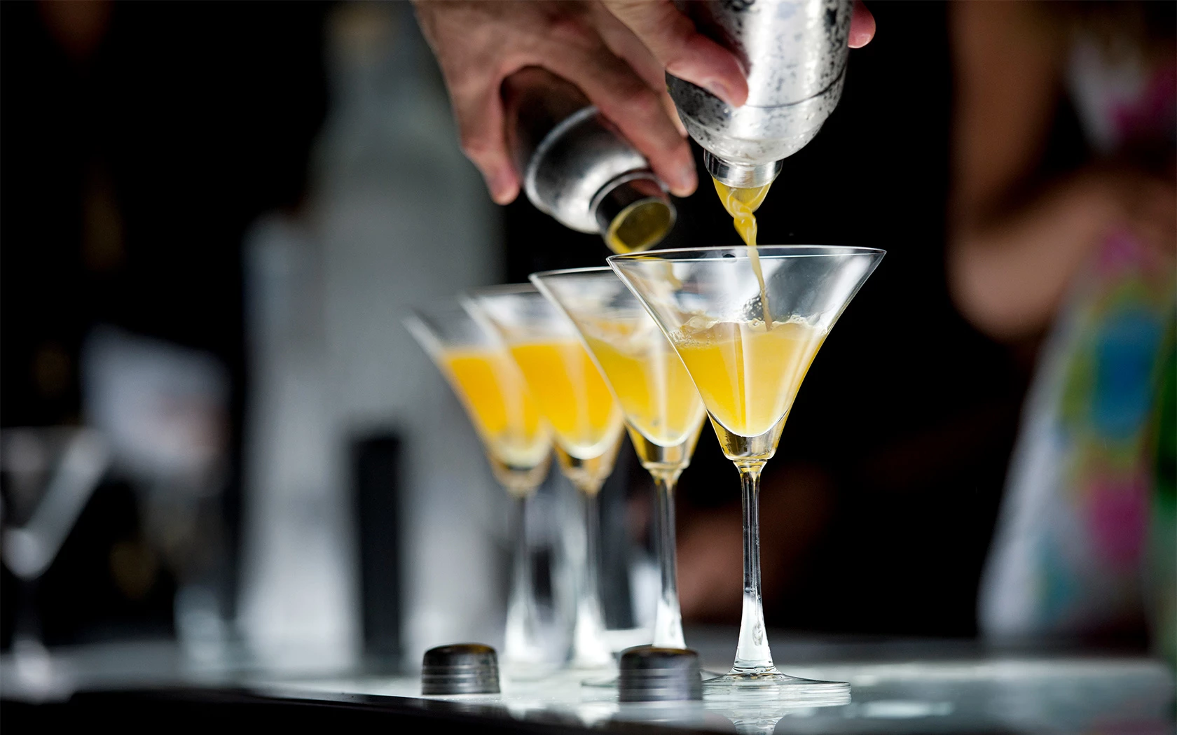 a hand pouring a drink into glasses