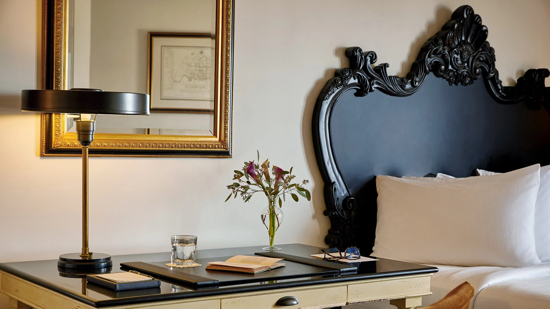 a desk with a glass of water and a vase of flowers on it
