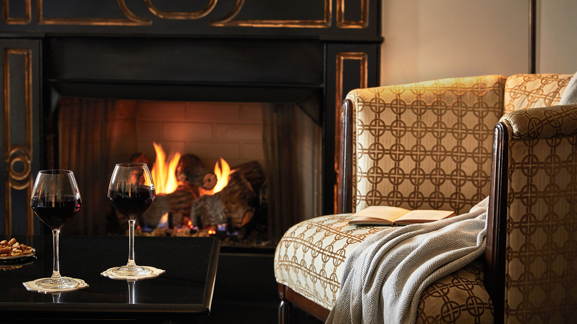 a glass of wine on a chair next to a fireplace