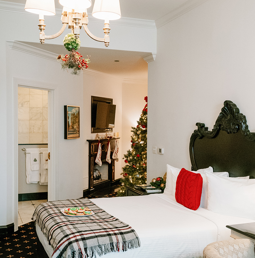 a bed with a blanket and a christmas tree in the background