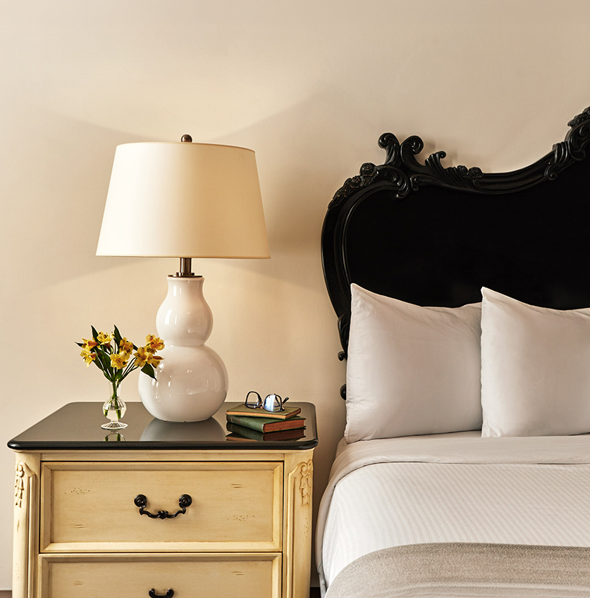 a lamp on a nightstand next to a bed