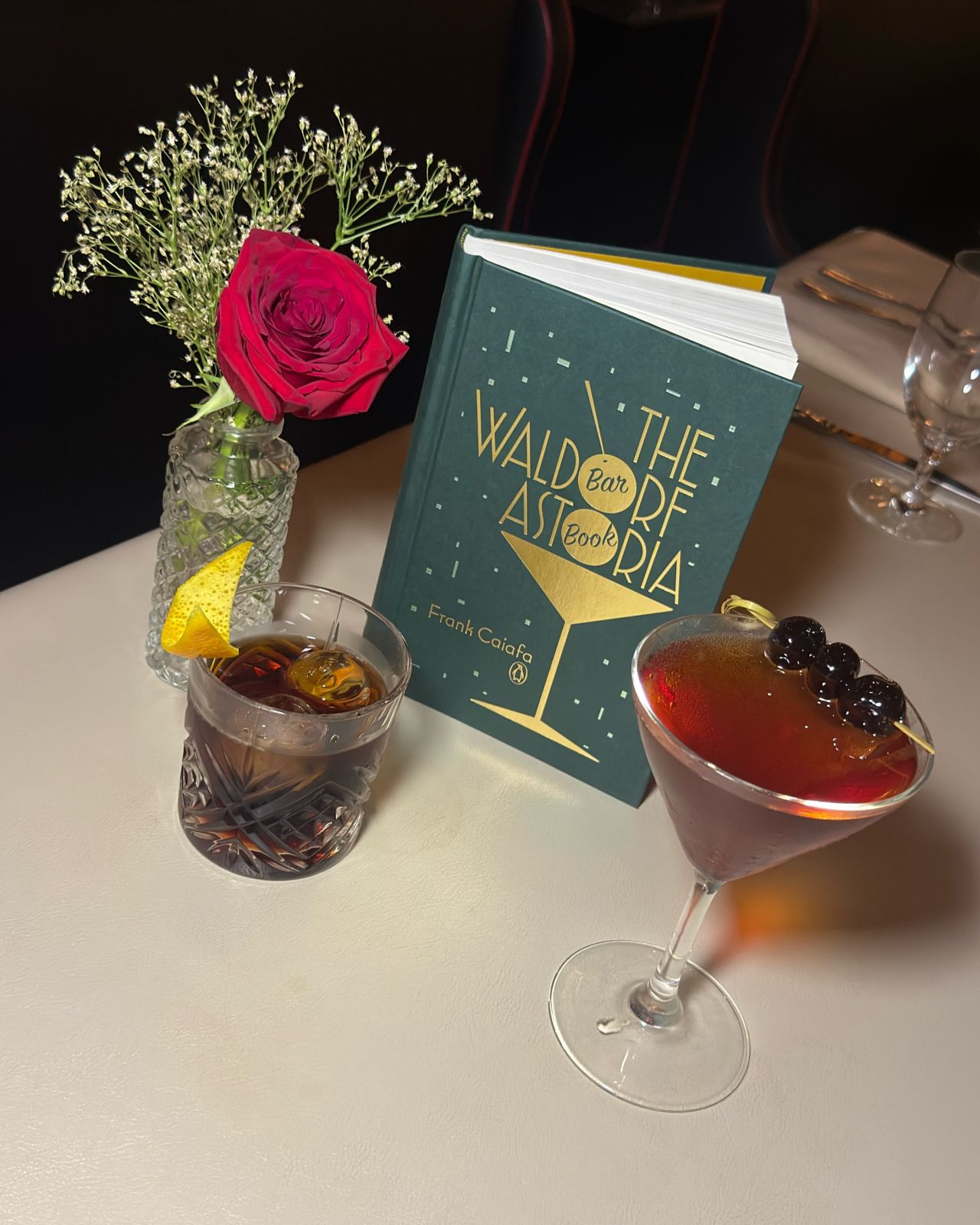 a book and glasses with drinks on a table