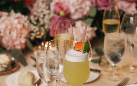 a table with glasses of drinks and flowers