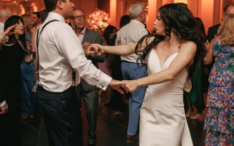 a man and woman dancing in a room with people in the background