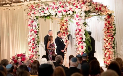 a man and woman standing under a floral arch
