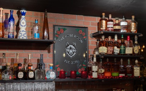 a shelf with bottles of alcohol and a sign on it