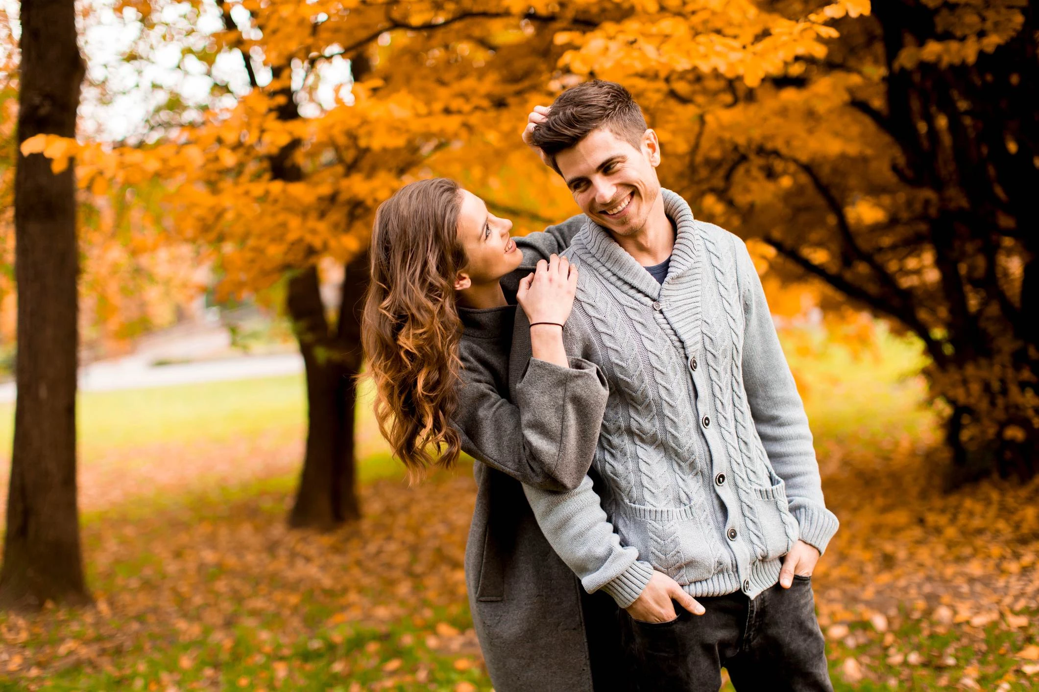 a man and woman standing together in front of a tree