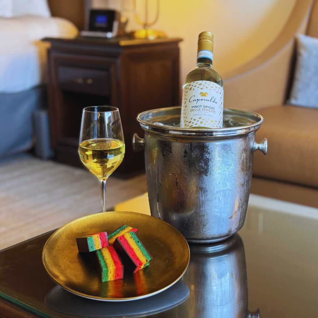 a bottle of wine in a bucket with a plate of food and a glass of wine