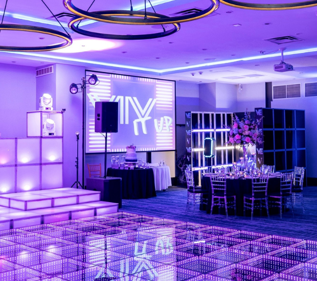 a room with a dance floor and a stage with purple lighting