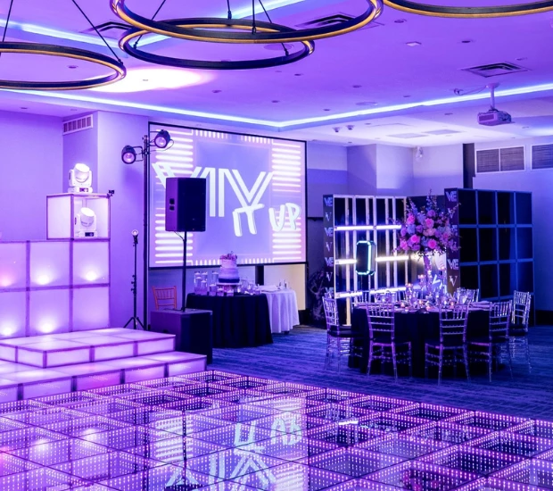 a room with a dance floor and a stage with purple lighting