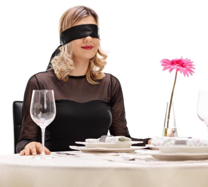 a woman sitting at a table with a blindfold