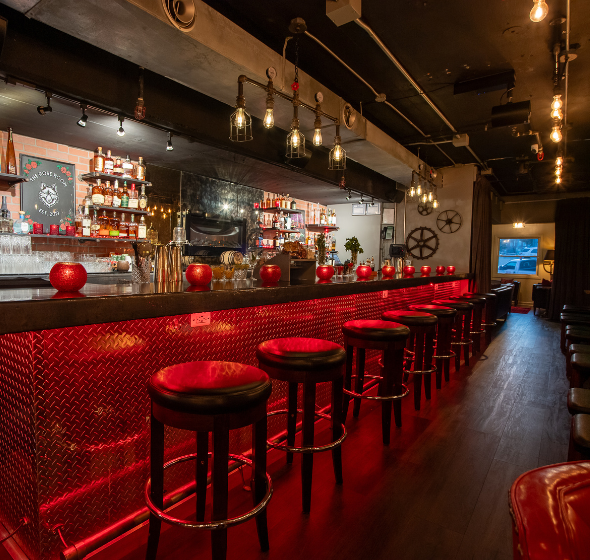 a bar with red stools and lights