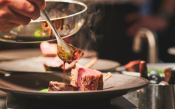 a person pouring sauce on a plate of food