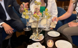 a group of people sitting at a table with a pyramid of martini glasses