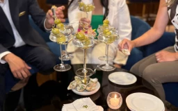 a group of people sitting at a table with a pyramid of martini glasses