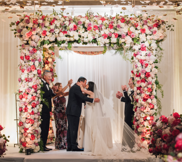 a bride and groom under a floral arch