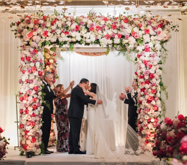 a bride and groom under a floral arch