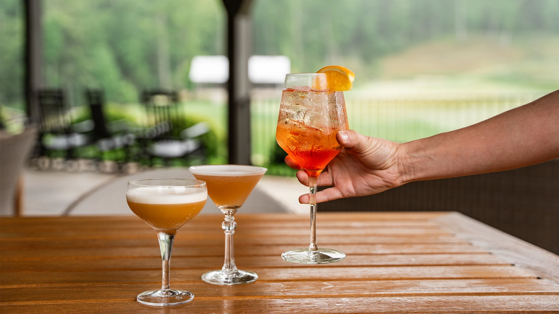 a hand holding a glass of orange liquid