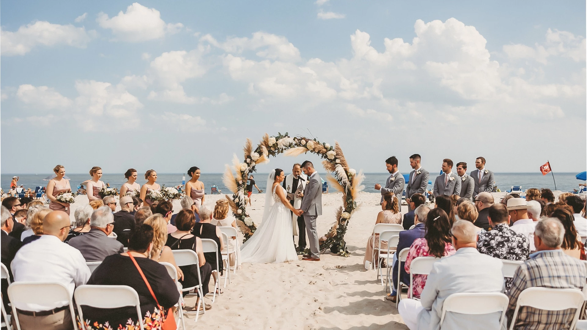 a couple in wedding attire under an arch on a beach