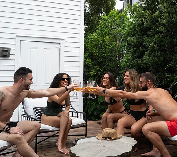 group of people cheering cocktails poolside