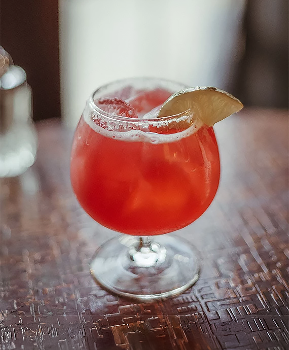 a glass with a drink and a slice of lime on it