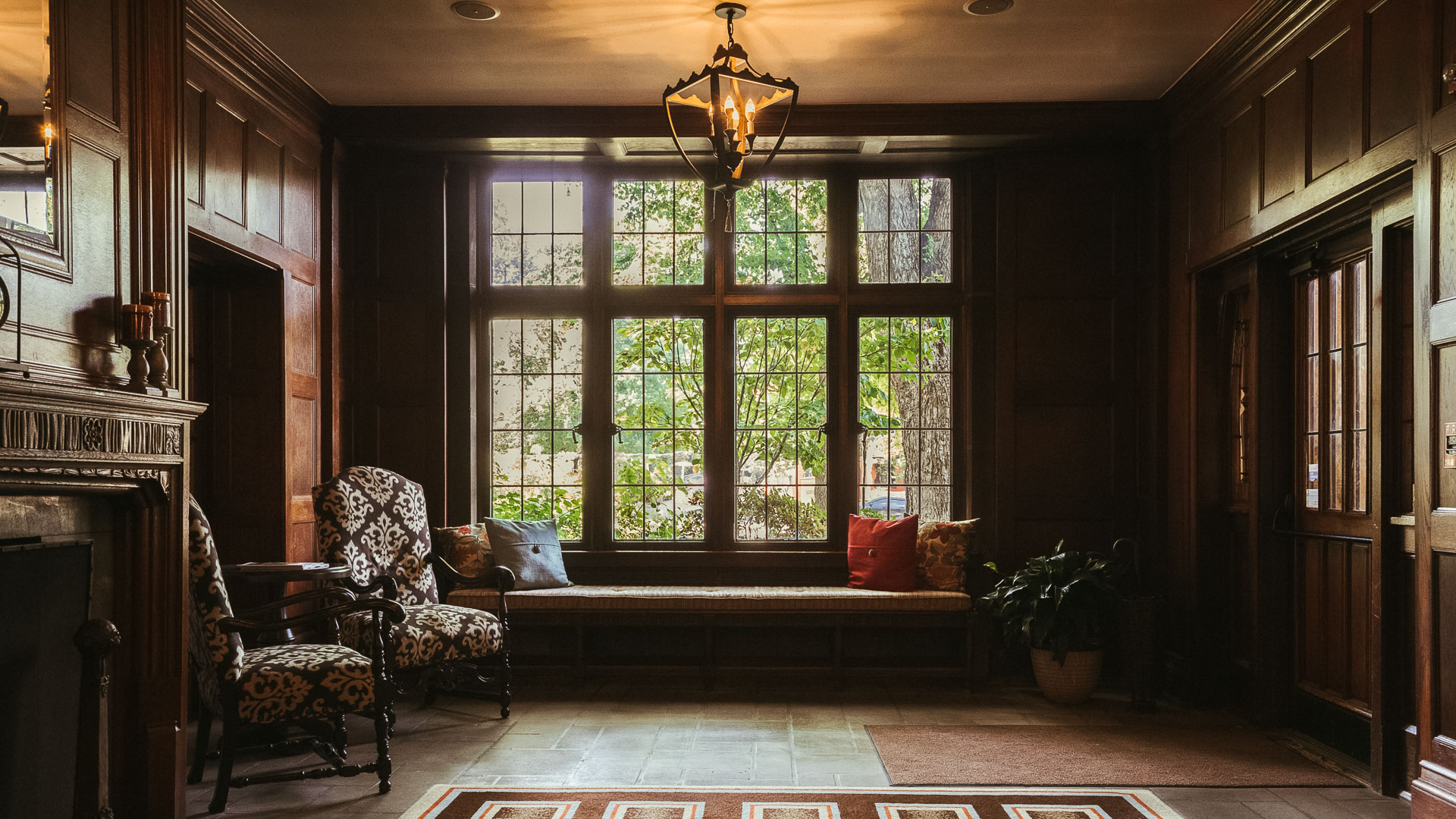 a room with a bench and a rug and a chandelier