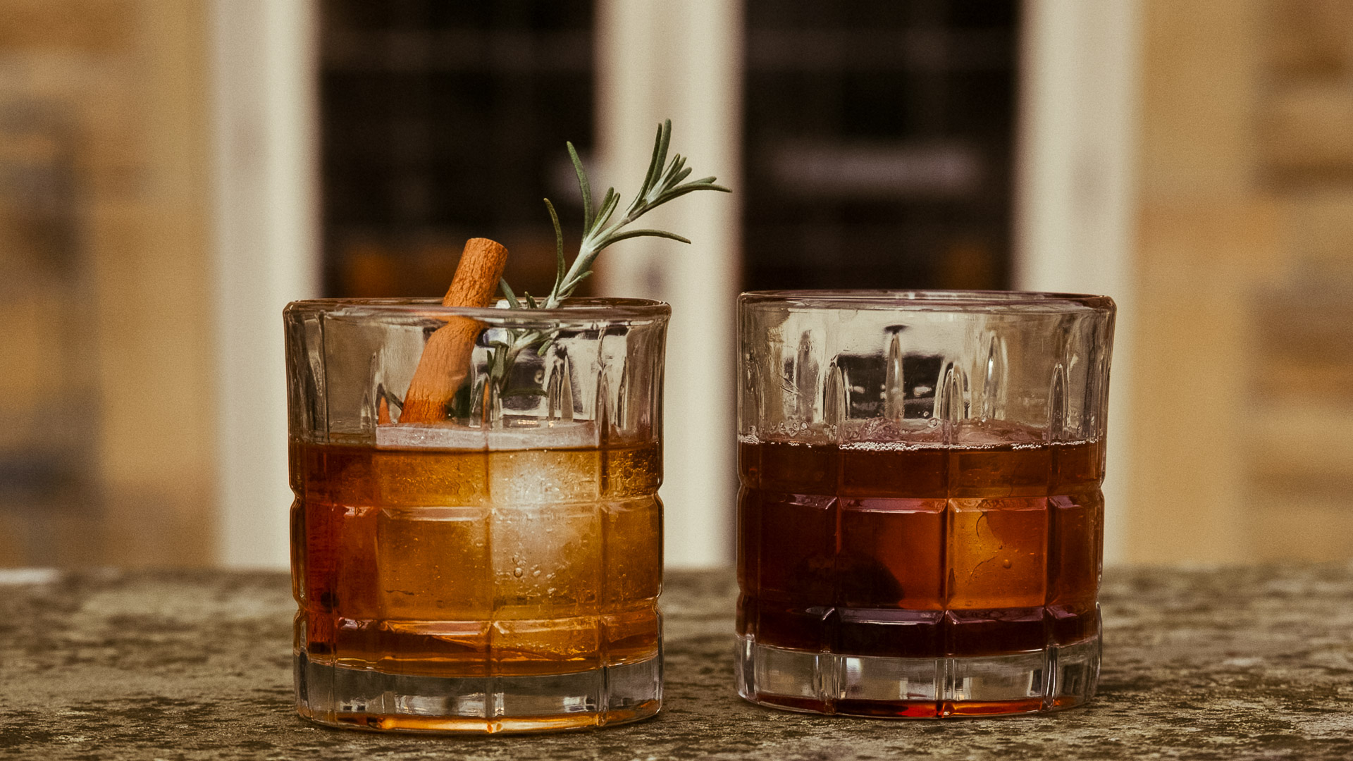 two glasses with brown liquid and a cinnamon stick
