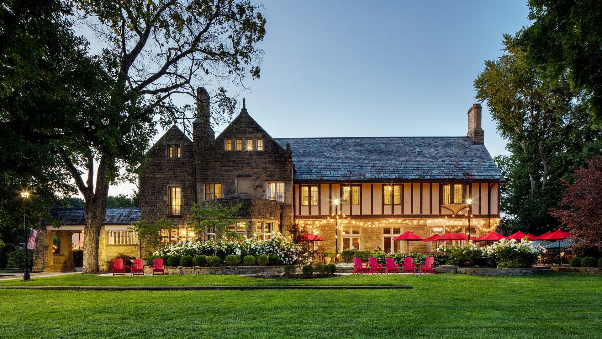 a large stone house with lawn and chairs
