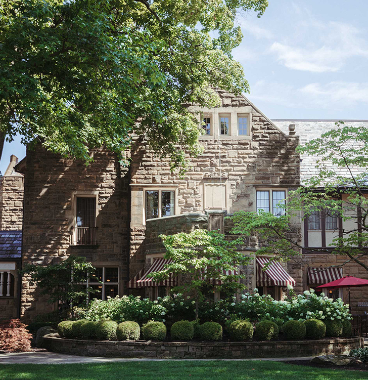 a stone building with trees and bushes