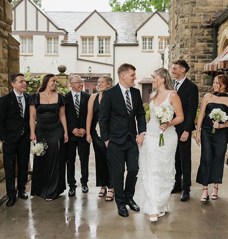 a group of people in black suits and white dresses walking together