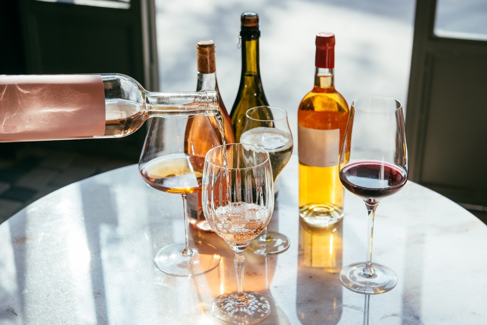 a person pouring wine into glasses