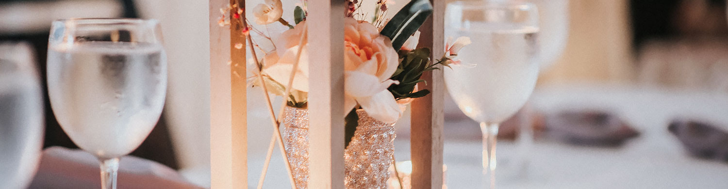 close up of a light pink flower table centerpiece in a sparkly vase under a lantern