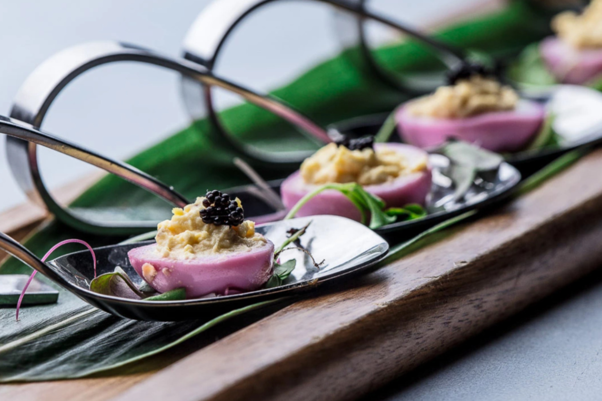 spoons with food on them on a wooden surface