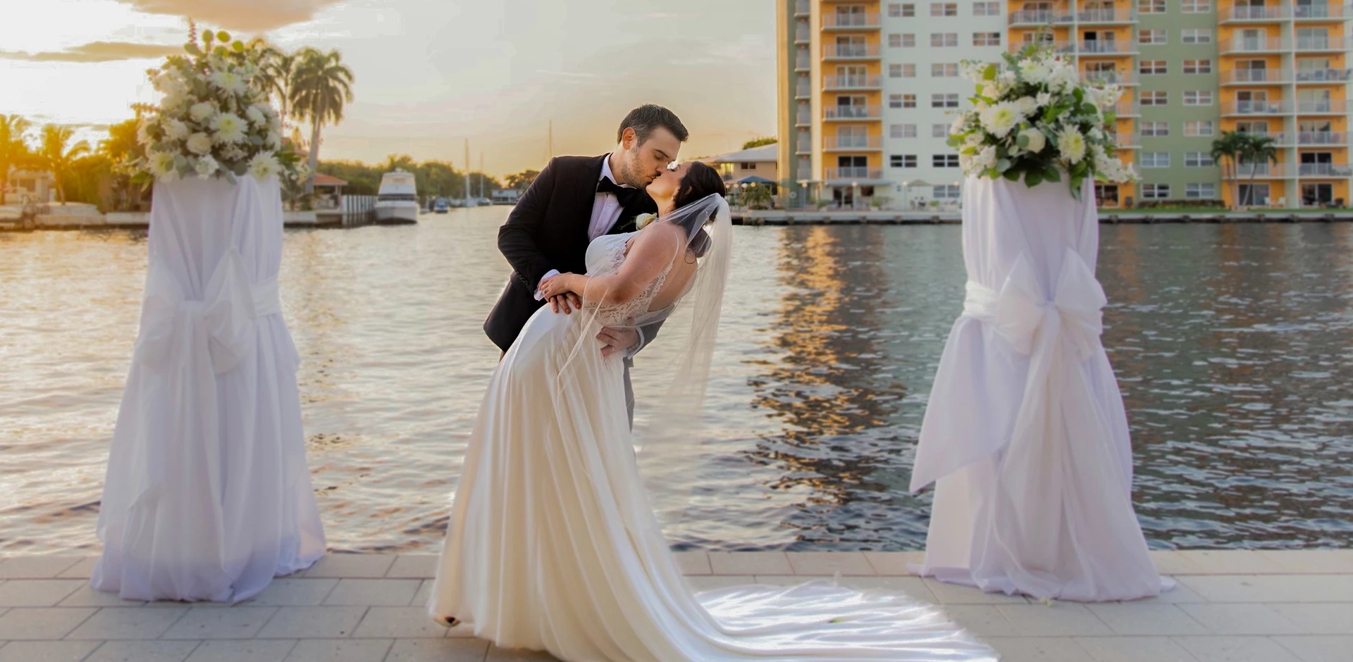 a man and woman kissing on a dock near water