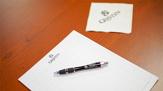 a table with a graylyn notepad and a pen with a napkin