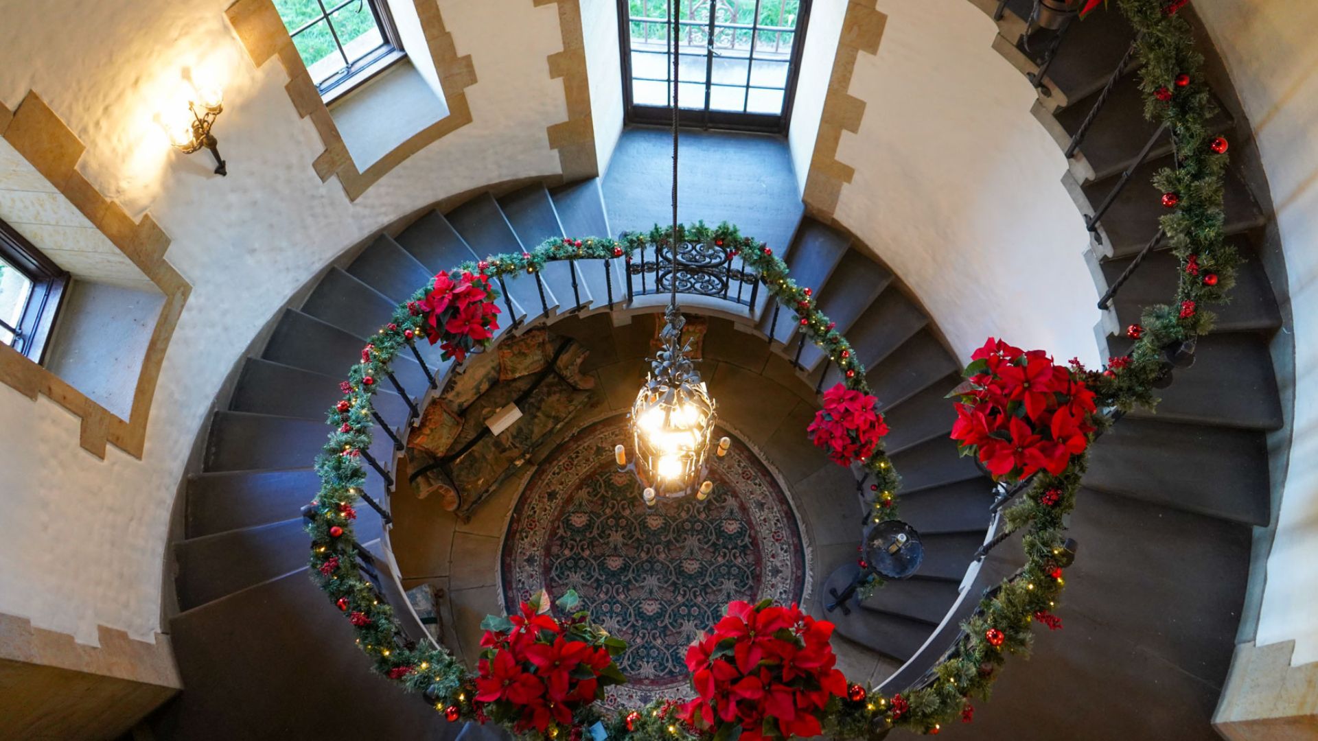 a spiral staircase with red flowers and lights