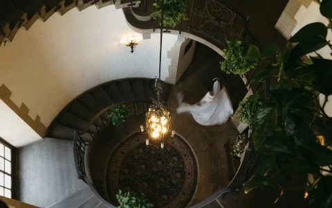a person in a white dress flying in a spiral staircase