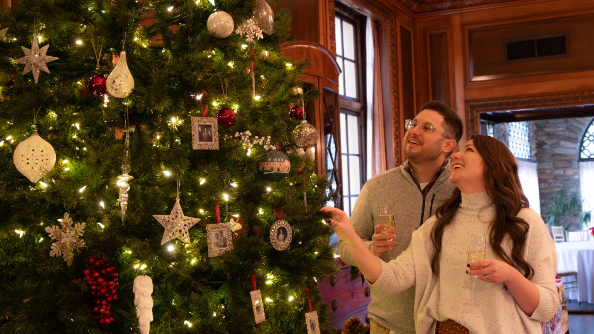 a man and woman standing next to a christmas tree