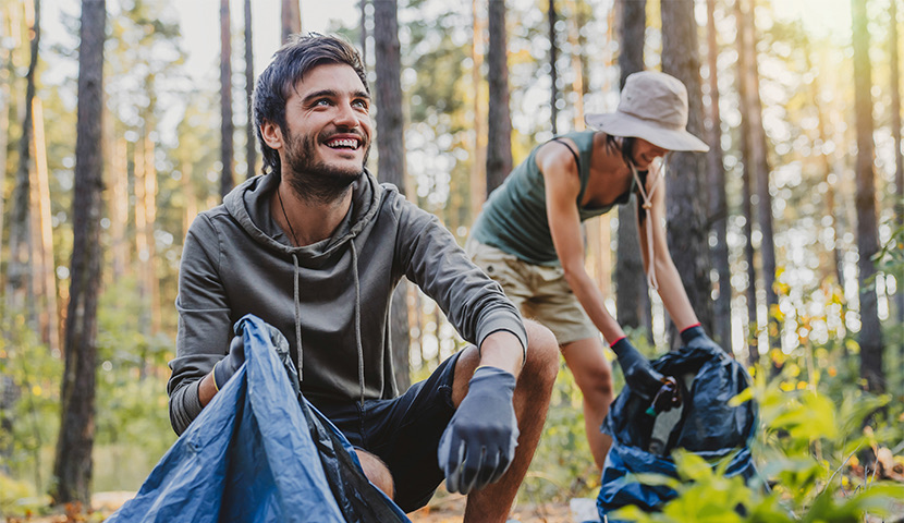 a smiling man kneeling in the forest