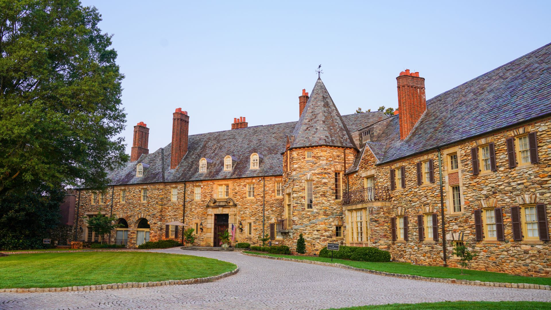 a large stone building with a driveway and grass