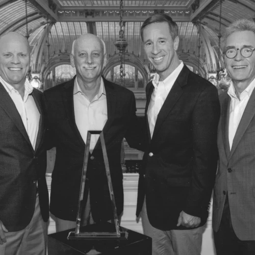 four businessmen standing behind a trophy